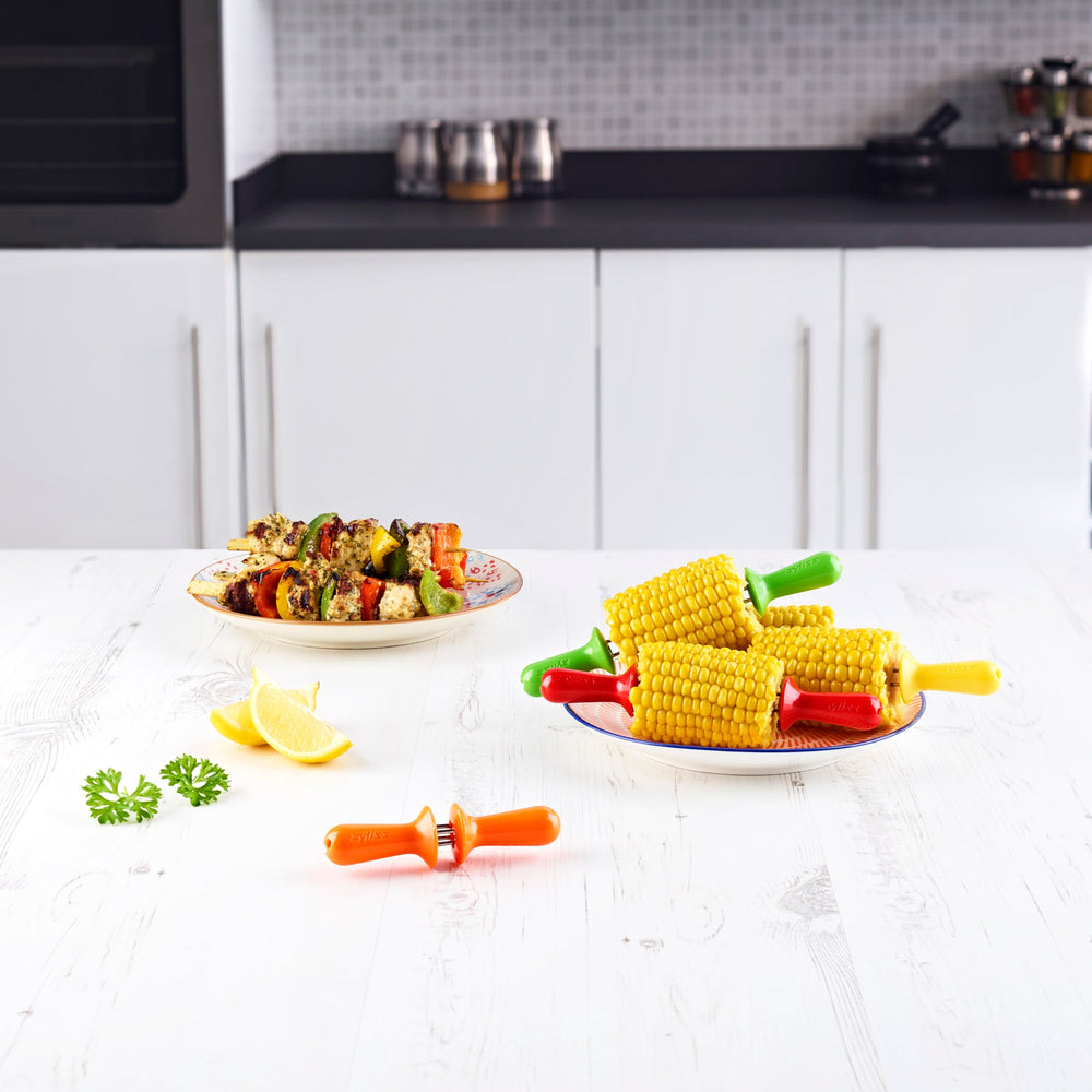 Zyliss Interlocking Corn Holders: Set of 8 dishwasher-safe holders with red, yellow, orange, and green plastic handles. Each has two metal prongs and interlocks to form four colorful pairs, shown arranged on a white background.