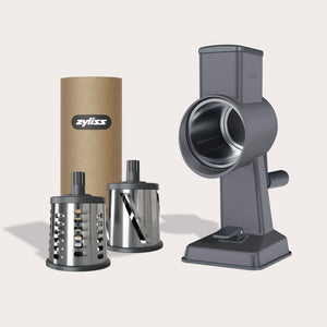 The Zyliss Gourmet Drum Grater Set features a gray base, two interchangeable stainless steel drums, and comes in a branded cylindrical box—an essential tool for any kitchen. 