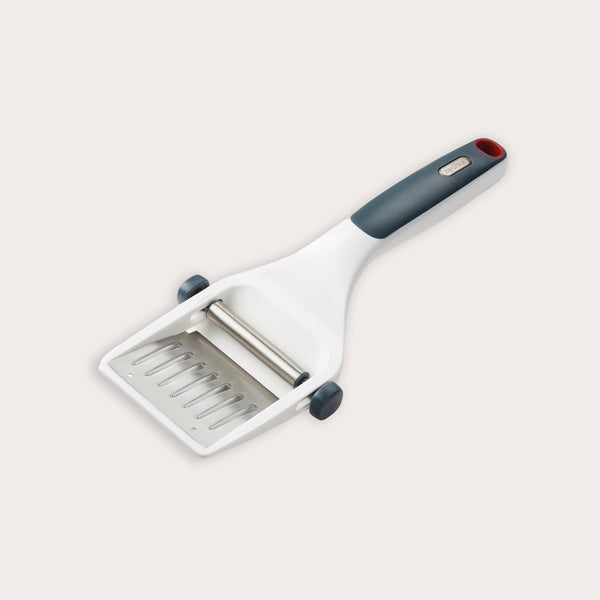 The Zyliss Dial & Slice Cheese Slicer features a white plastic body, gray and red ergonomic handle, and an adjustable blade for slicing cheese to your preferred thickness.