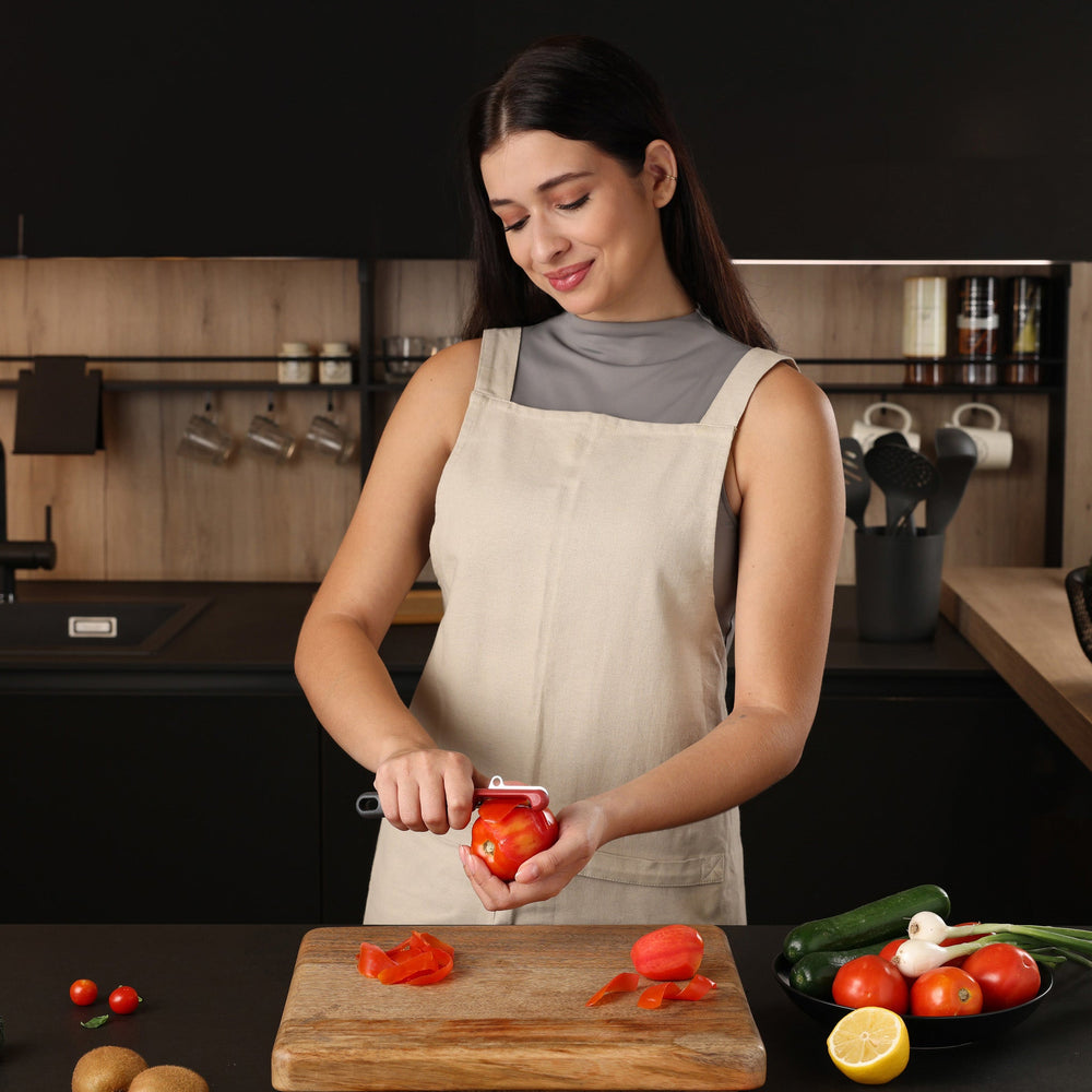 The Zyliss Soft Skin Peeler features a dark gray handle with a small end hole, a red top, and a horizontal stainless steel blade. This eco-friendly peeler is displayed on a plain light background.