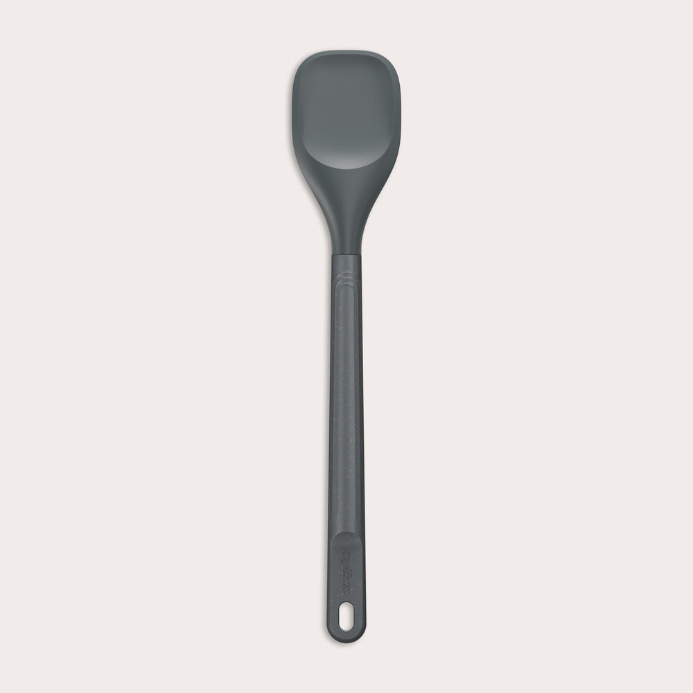 #medium The Zyliss Spoontula is dark gray, with a silicone head, long ergonomic handle, and a gently rounded rectangular bowl, pictured on a plain light background. #Medium