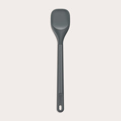 #medium The Zyliss Spoontula is dark gray, with a silicone head, long ergonomic handle, and a gently rounded rectangular bowl, pictured on a plain light background. #Medium