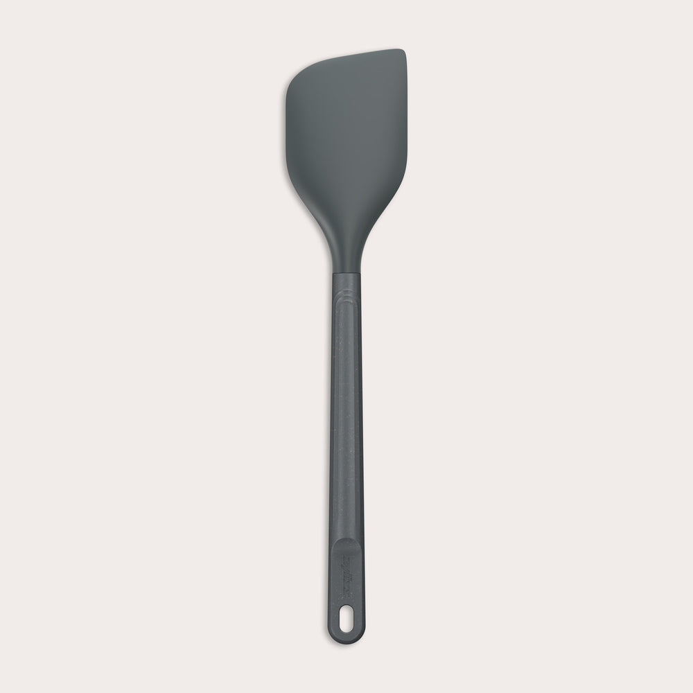 A dark gray Zyliss Spatula with a long handle and a slightly angled, heat-resistant silicone head is displayed on a plain white background. #Large