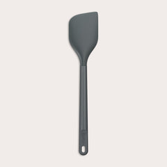 A dark gray Zyliss Spatula with a long handle and a slightly angled, heat-resistant silicone head is displayed on a plain white background. #Large