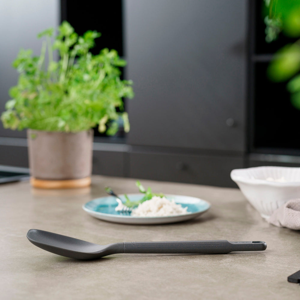 #large A durable Zyliss Spoon in dark gray silicone, featuring a long handle with a hole at the end, displayed on a plain light background. #Large