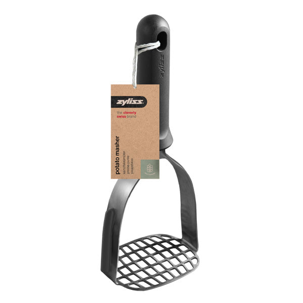 A black potato masher with a wide, grid-patterned base and a curved handle. A brown tag labeled Zyliss potato masher is attached with a white string.