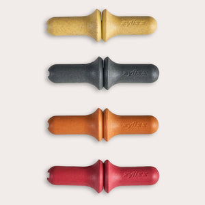 The Zyliss Corn Holders 4 Piece Set features cylindrical holders with ergonomic handles in yellow, black, orange, and red, each with a notch at one end, shown vertically on a light background.