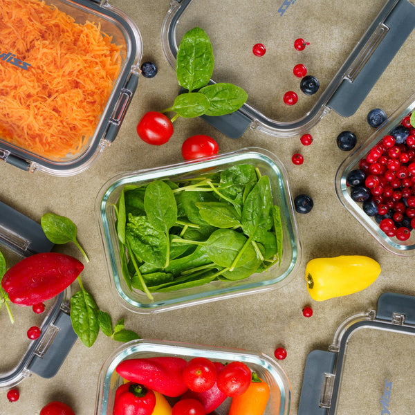 Zyliss Glass Containers filled with shredded carrots, fresh spinach, and assorted berries are surrounded by loose spinach leaves, cherry tomatoes, sweet peppers, and various berries—ideal for meal prep on a gray surface. #1.52L/1.61qt